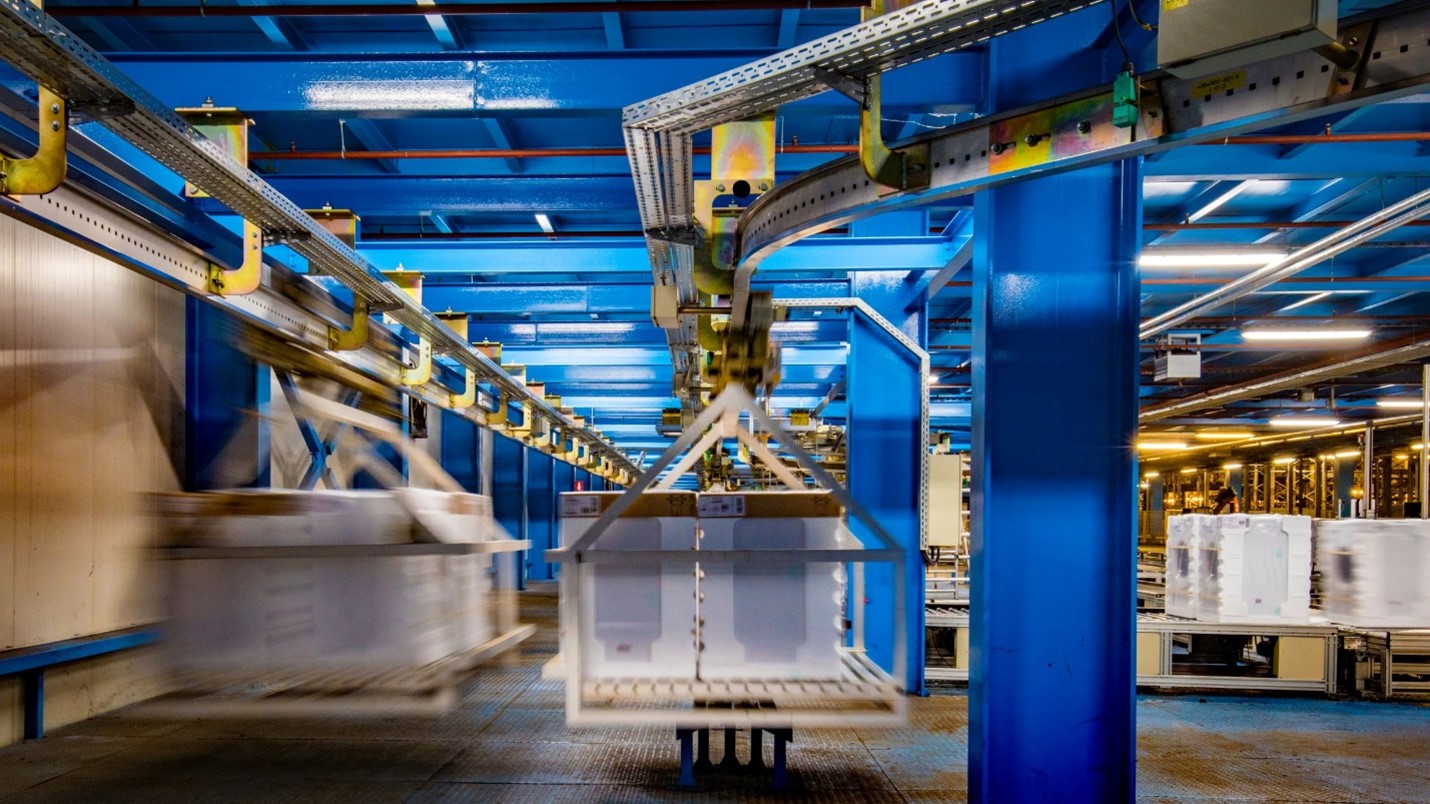 A blue-lit factory interior with blue walls, machinery, and equipment, showcasing the integration of a Morn cargo lift for streamlined operations.