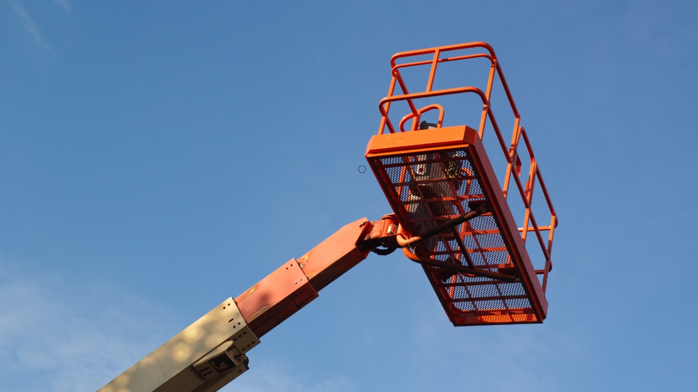 A man standing on a Morn lift platform, wearing a hard hat and safety gear, ready to work at a construction site.
