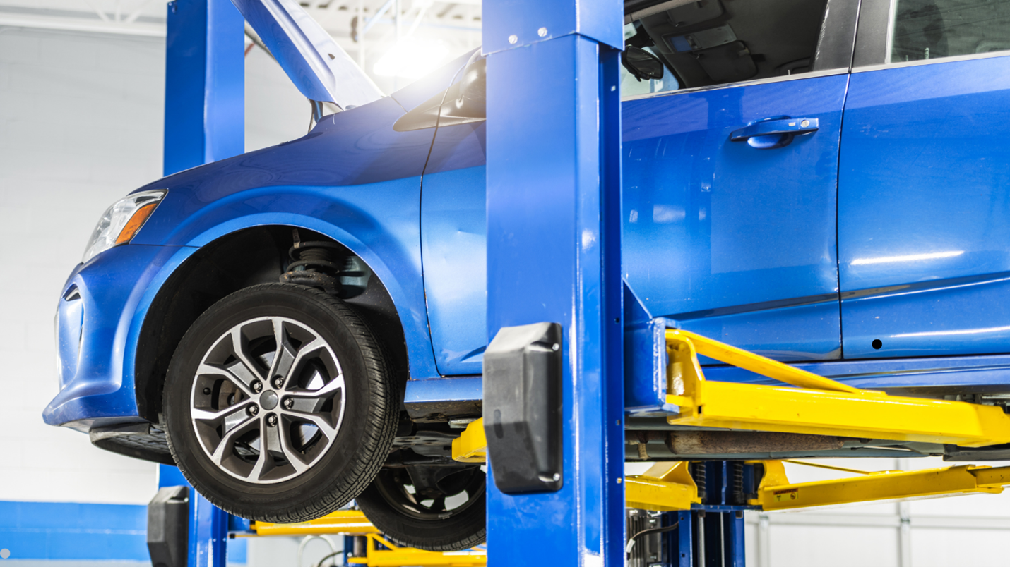 Useful Car Lifts In Auto Repair: Enhancing Service Capabilities - MORN LIFT A blue car being lifted on a morn lift, showcasing maintenance or repair work being done on the vehicle